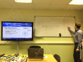 На экране слева показана структура оптического волокна, преподаватель на доске поясняет устройство и свойства оптоволокна